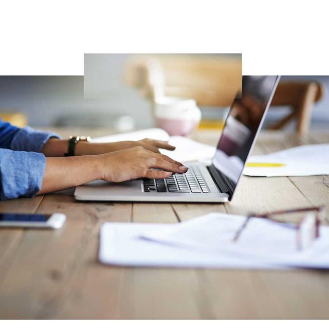 A close up image of a woman's hands typing on a laptop.