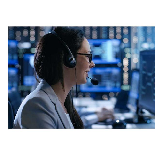 A side profile image of a female dispatcher wearing a headset, smiling and speaking. Behind her, we see the lights and screens from a bustling emergency dispatch center.