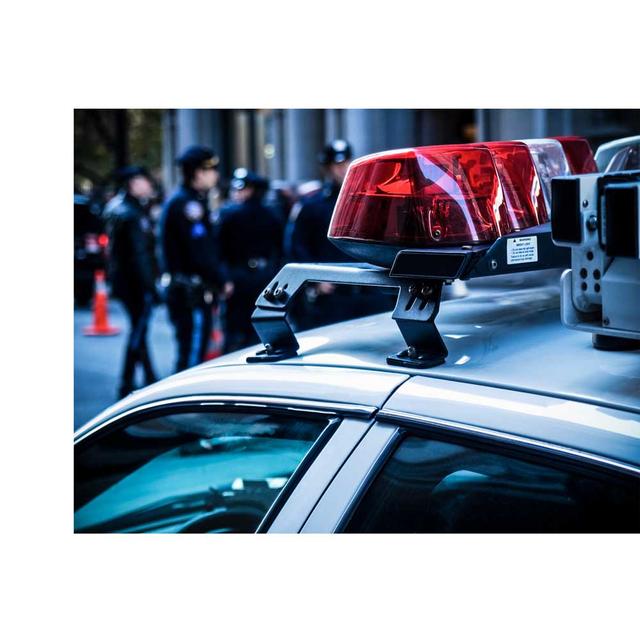 A close up photo of a patrol car's emergency lights. There is a group of police officers in the background.