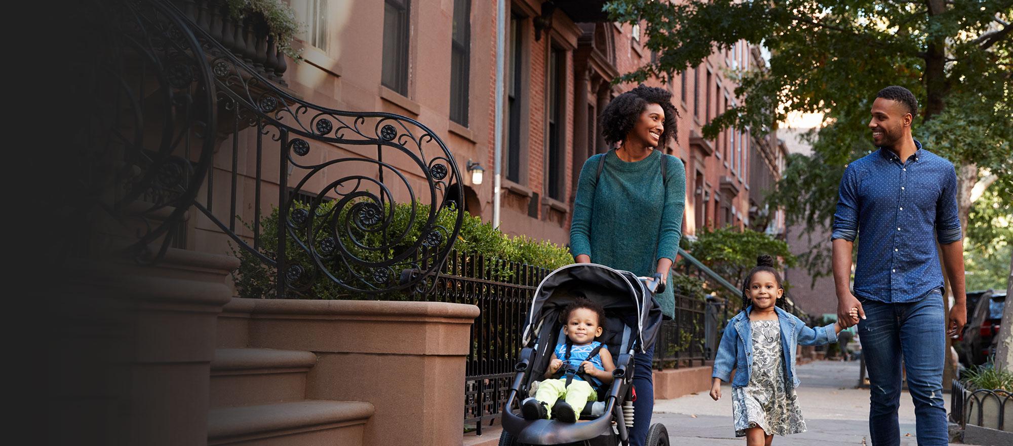Happy family safely walking down the street of their community.
