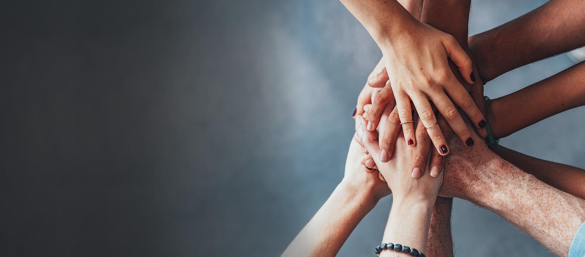 Many hands together on top of one another, to visualize teamwork.