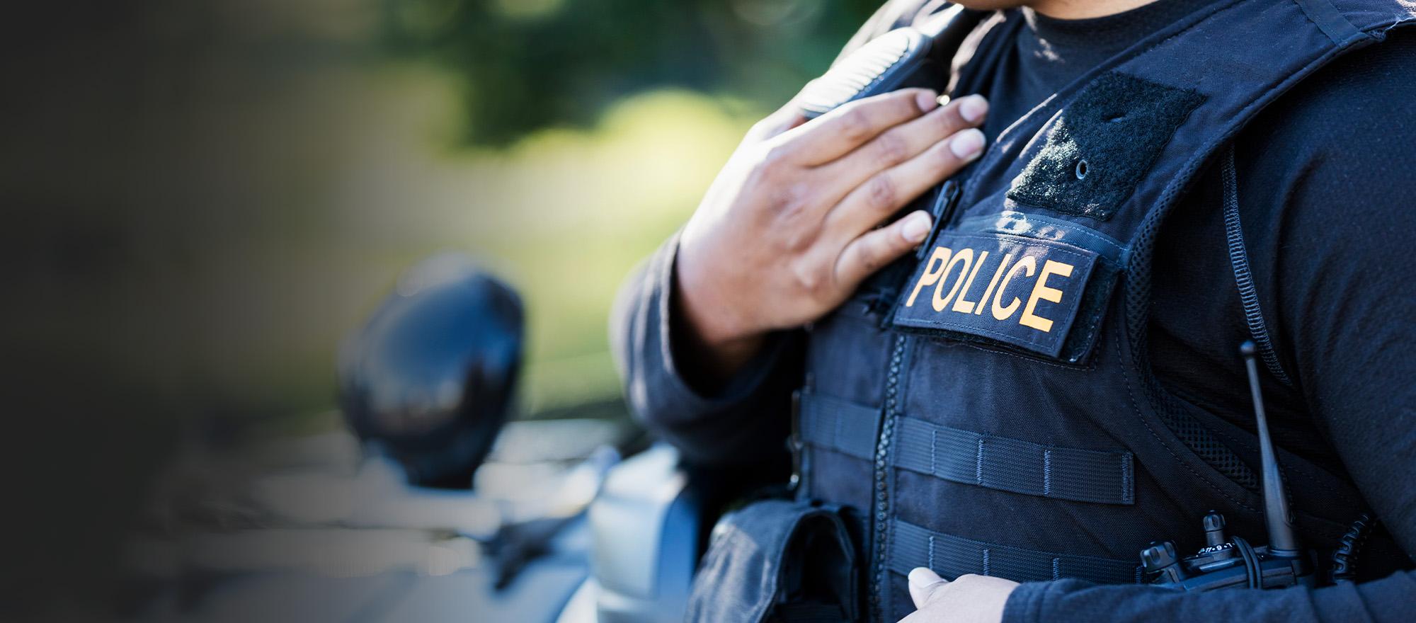 Mobile optimized image of a female police officer with her hand placed over her heart.