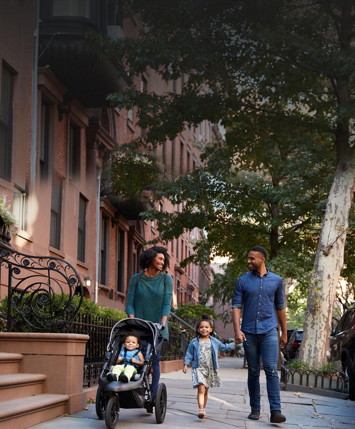 Happy family safely walking down the street of their community.