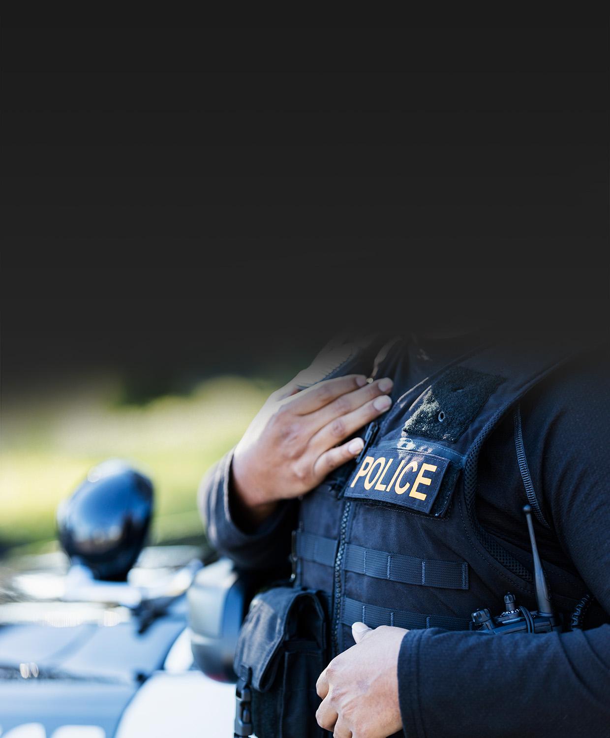 Mobile optimized image of a female police officer with her hand placed over her heart.