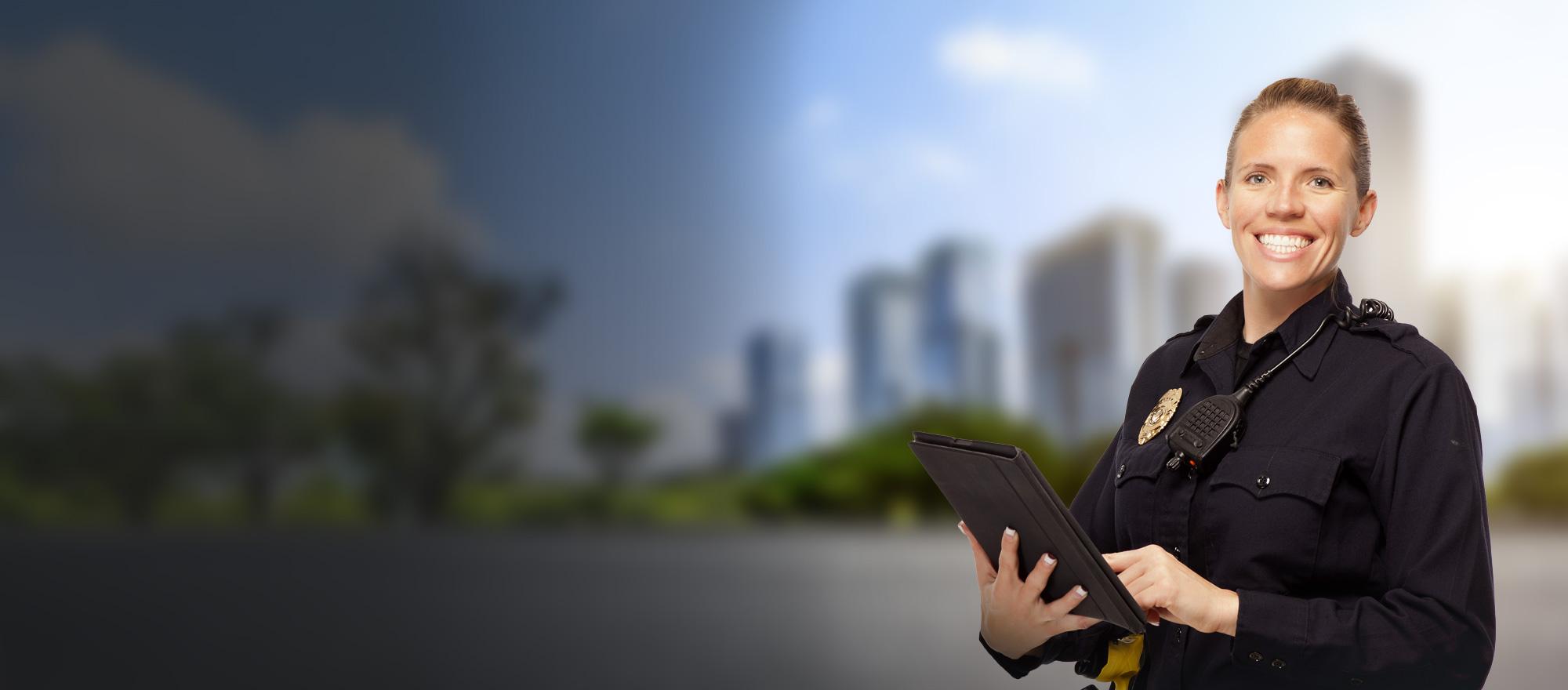 A female officer is smiling as she holds a tablet in her hands.