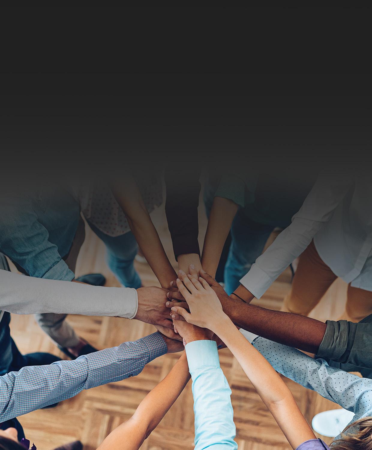 Many diverse hands together on top of each other, meant to display the idea of teamwork.