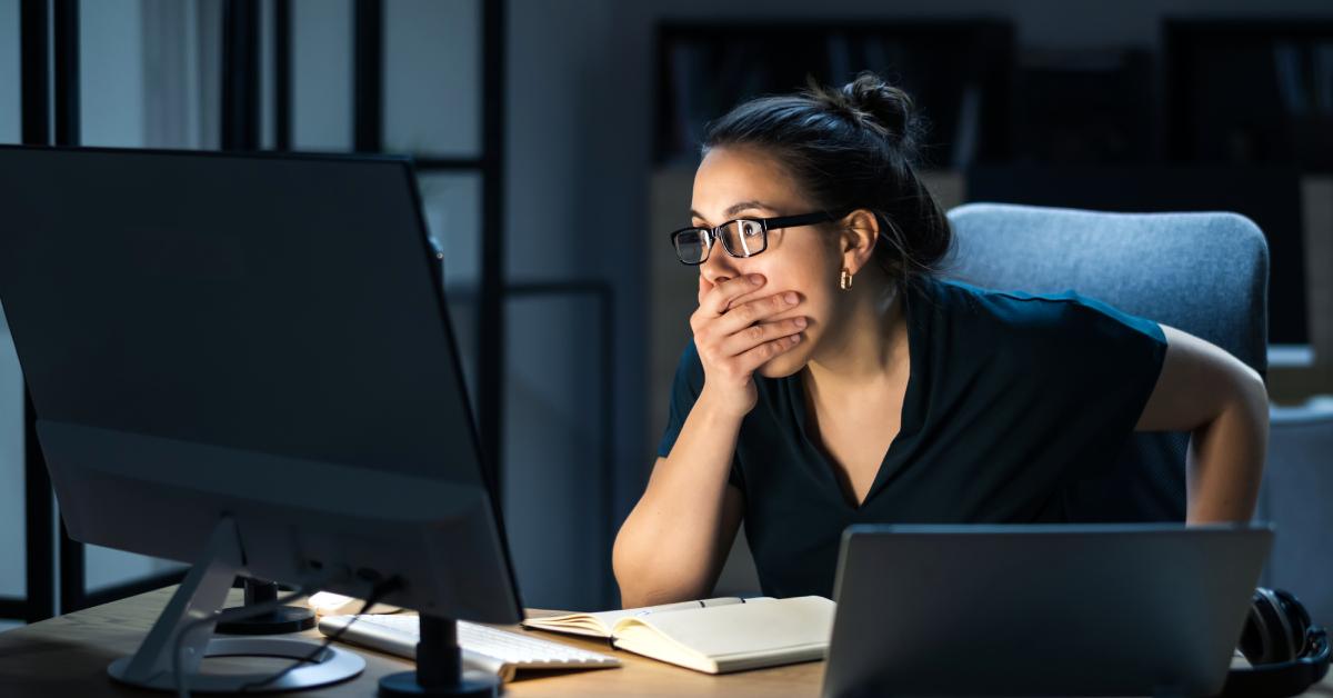 Image depicting a woman in shock discovering a potential ransomware attack on her computer system.