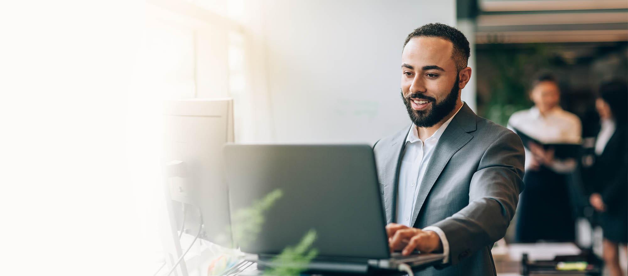 A background image of a man smiling while looking at his laptop.