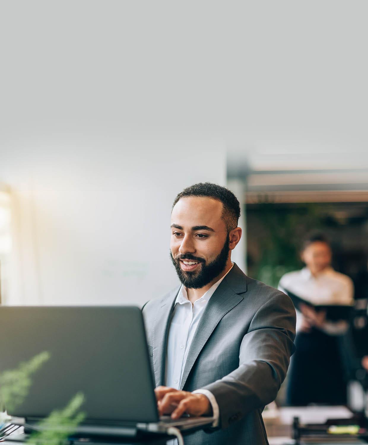 A background image of a man smiling while looking at his laptop.