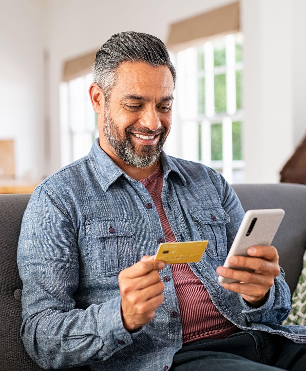 A man paying for something holding his mobile device in one hand and his phone in the other.