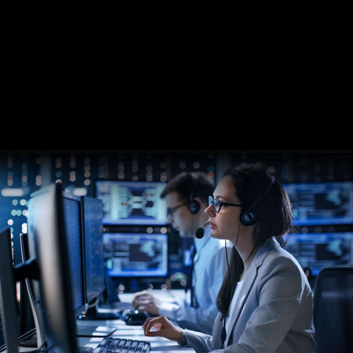 A woman working in a 911 Dispatch Center is talking over a headset.