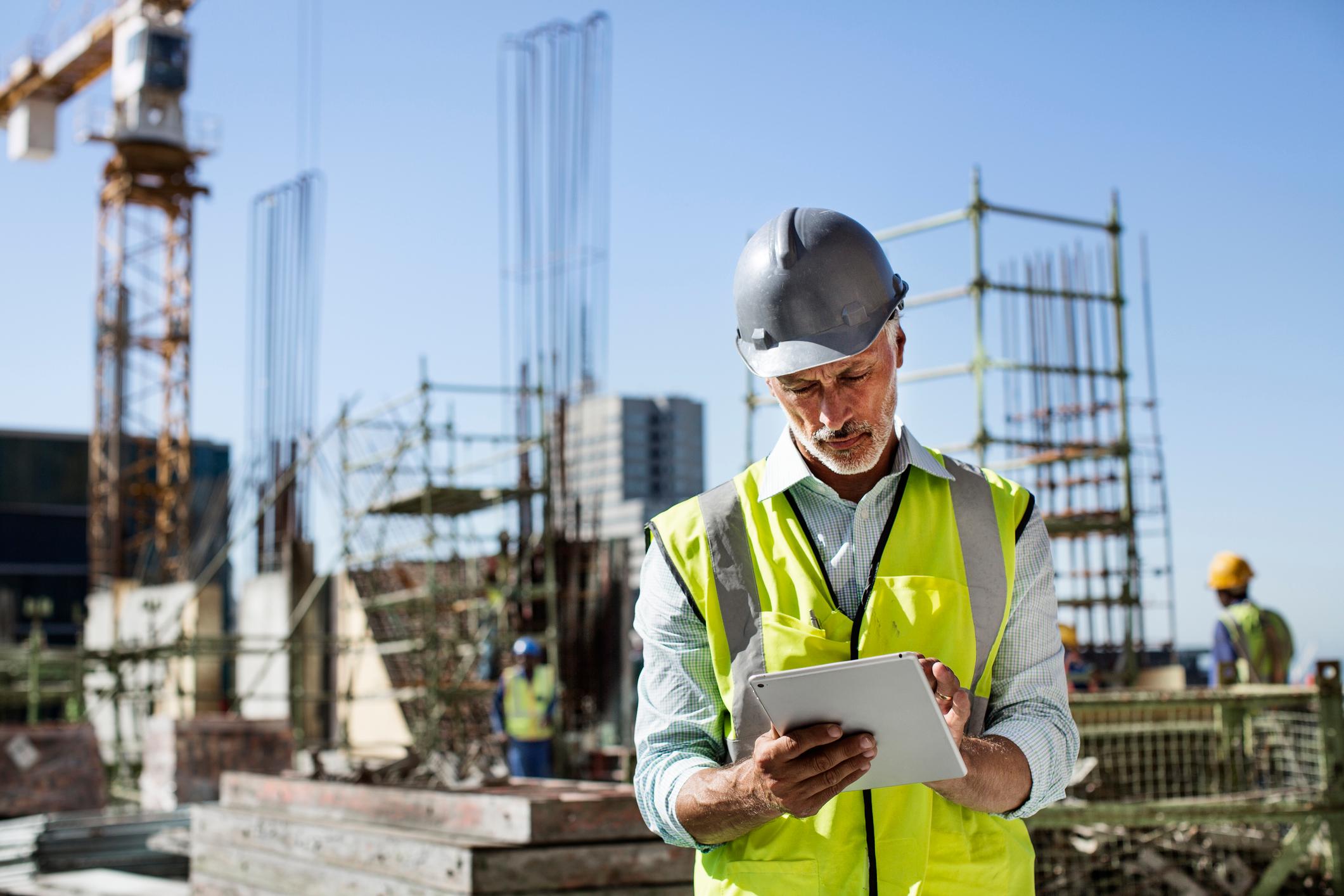 construction worker using modern community development technology on mobile device