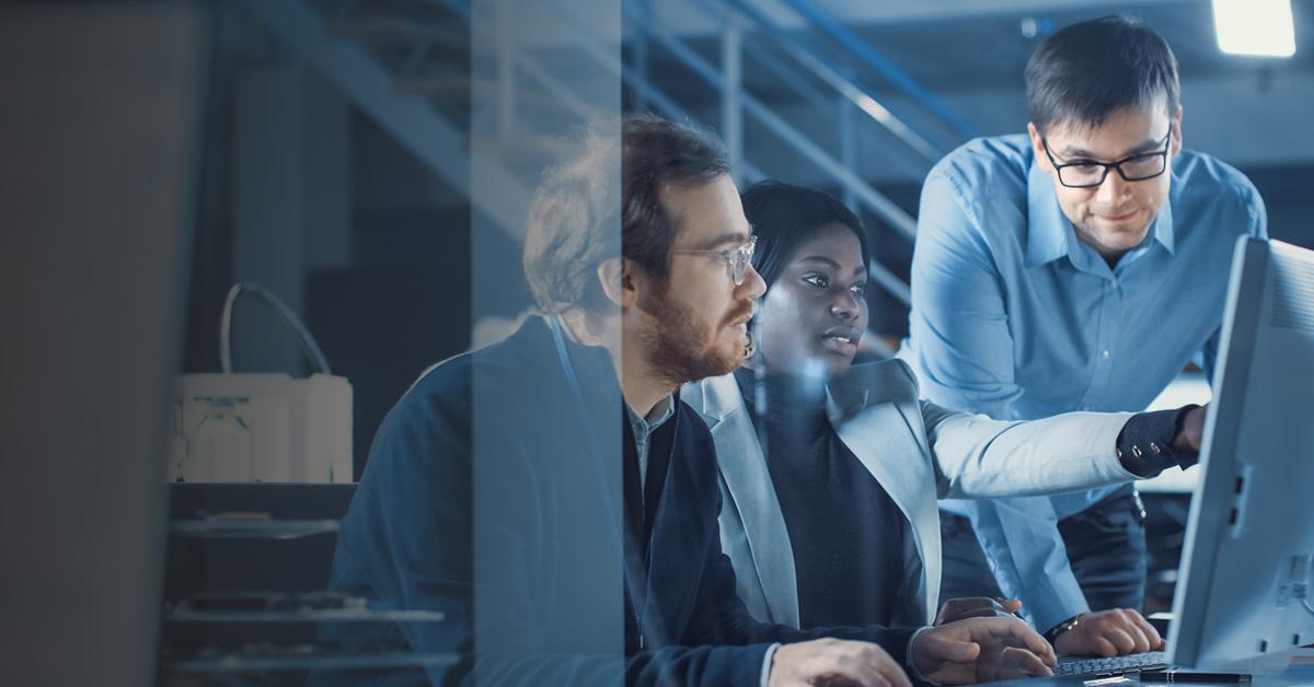 Three co-workers working together in front of a computer screen