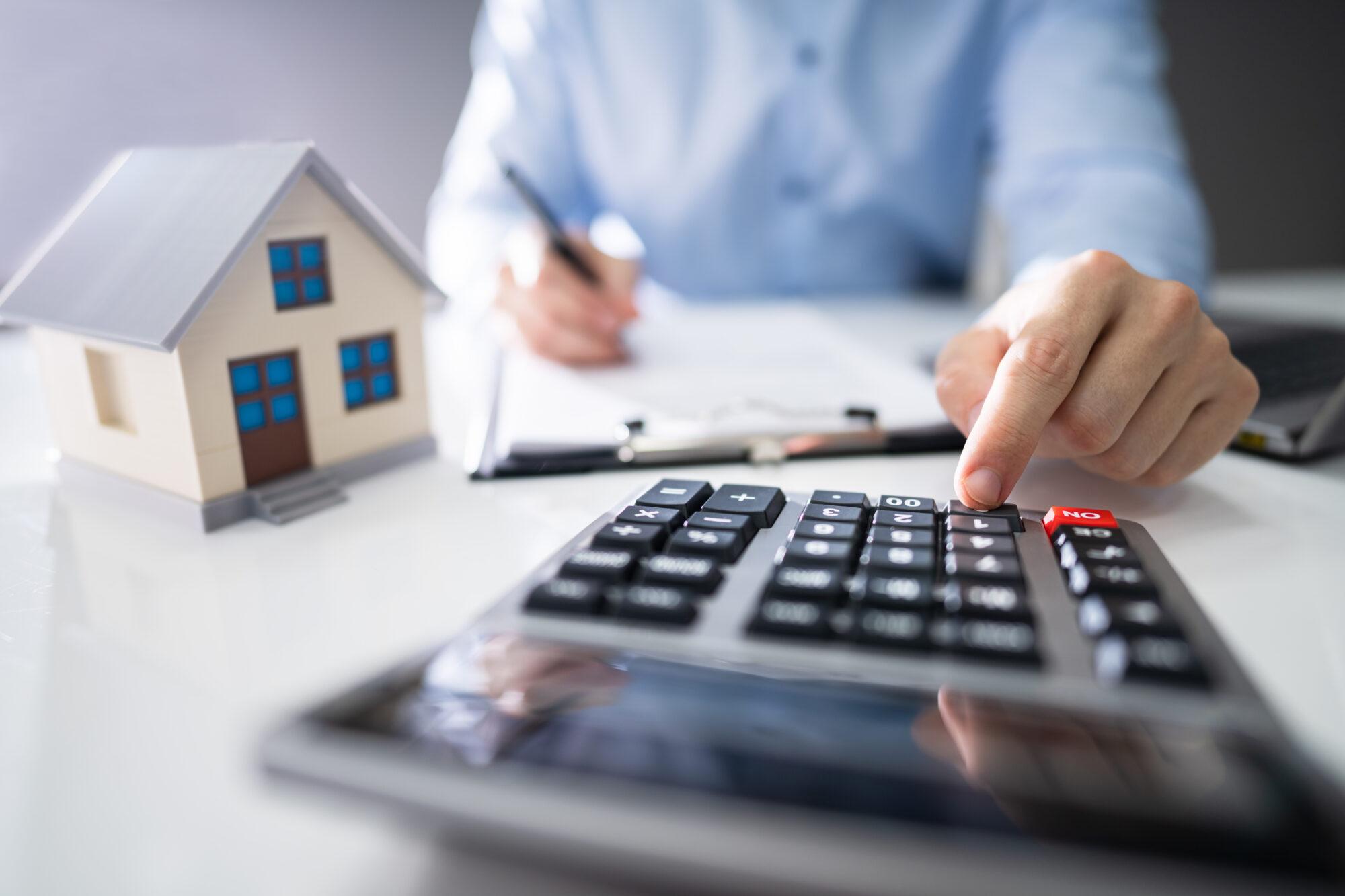 A homeowner sitting at a table using a calculator to report his property taxes by writing on a notepad