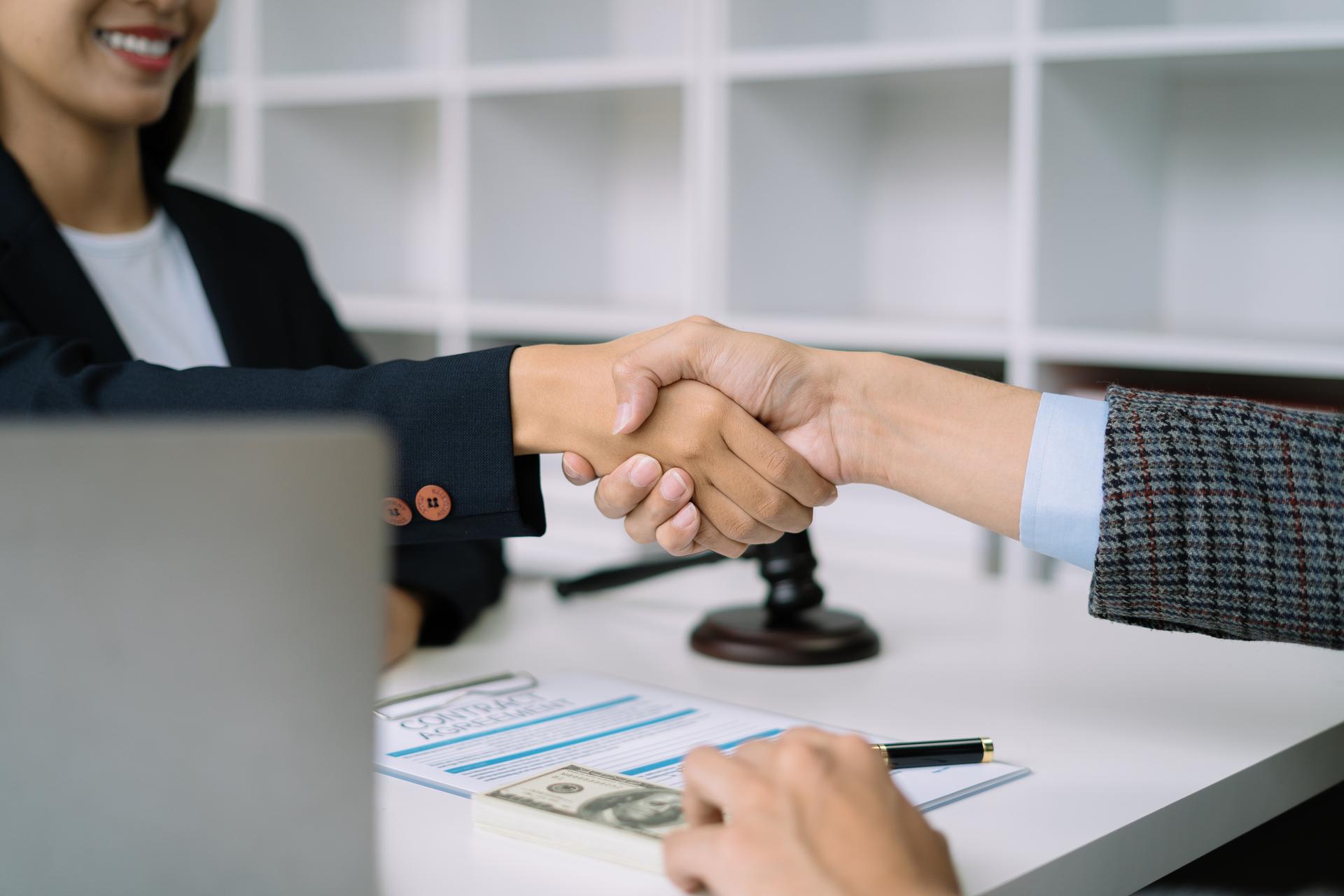 Lawyer shaking hands with client after discussing final contract agreement.