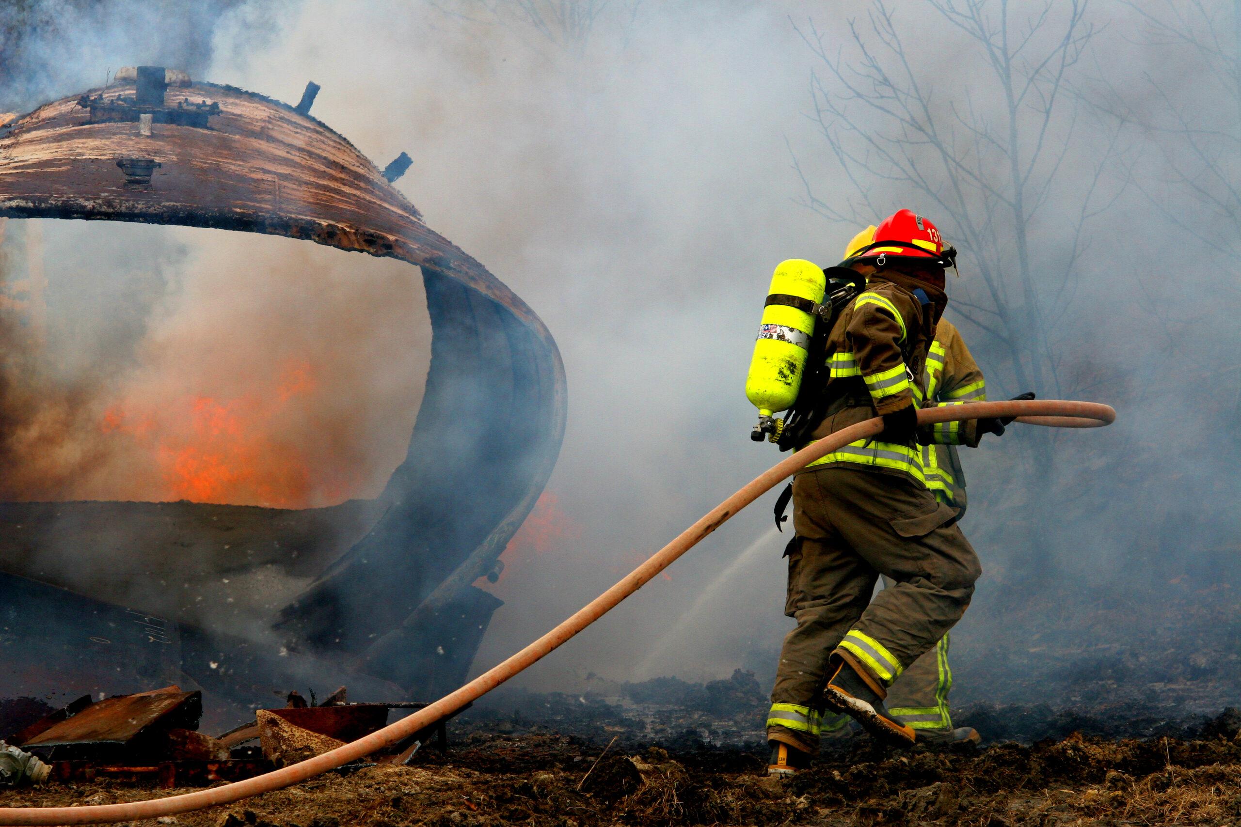 Firemen fight with an outdoor fire trying to keep it from spreading.