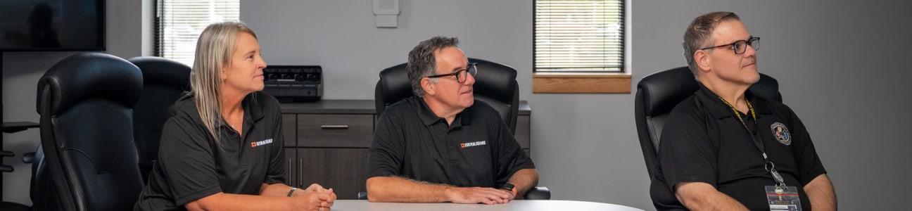 Two CentralSquare employees anda customer sitting at a table looking at a screen together