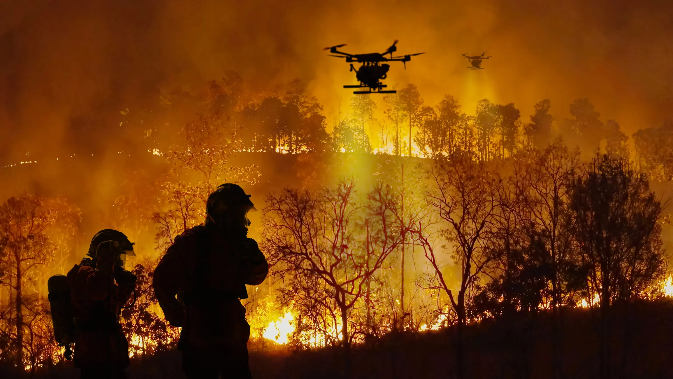 Firefighting drones flying over a wildfire.